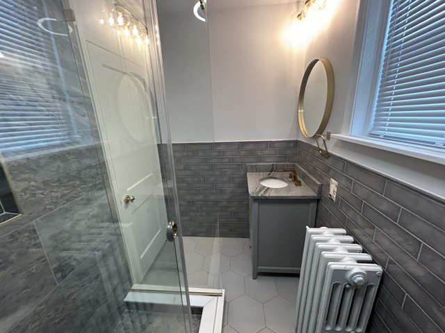 Teal tiled walk-in shower beside a dark vanity