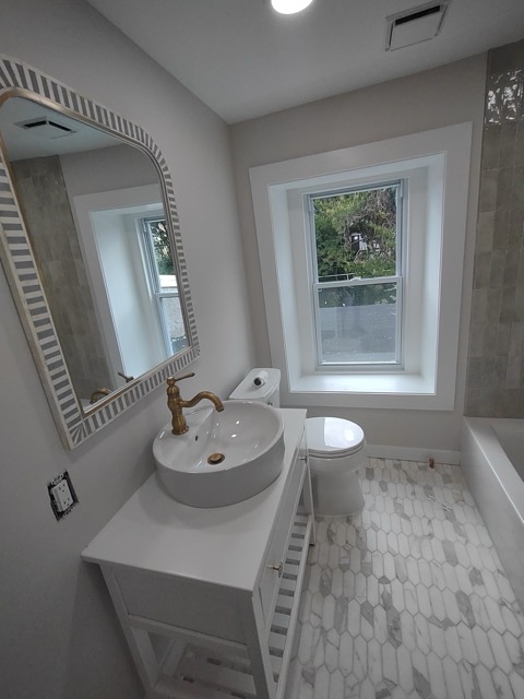 Teal tiled walk-in shower beside a dark vanity