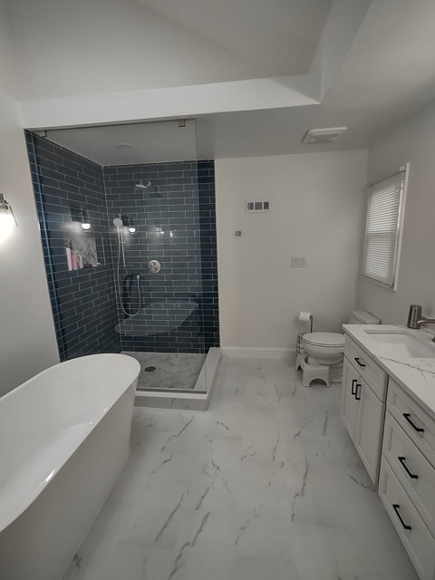Teal tiled walk-in shower beside a dark vanity