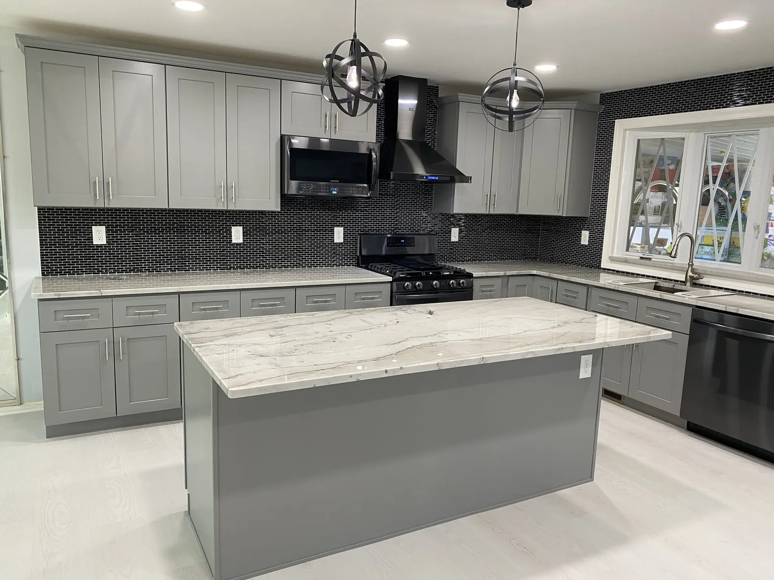 White kitchen remodel with an island and gray subway tile