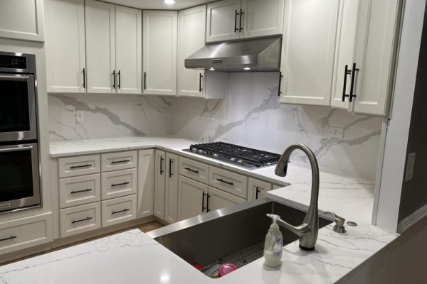 Elegant kitchen remodel with white shaker cabinets, quartz countertops, marble backsplash, stainless steel appliances, and farmhouse sink in PA