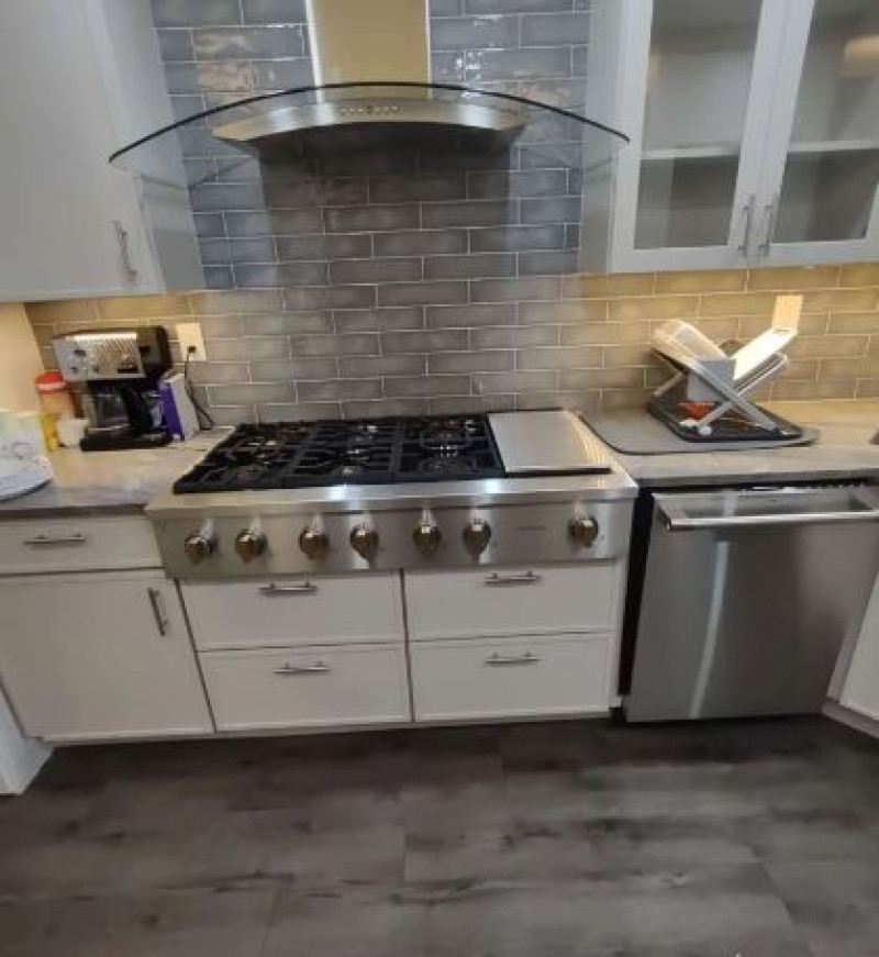 Contemporary kitchen with stainless steel gas range, glass subway tile backsplash, and modern range hood in PA