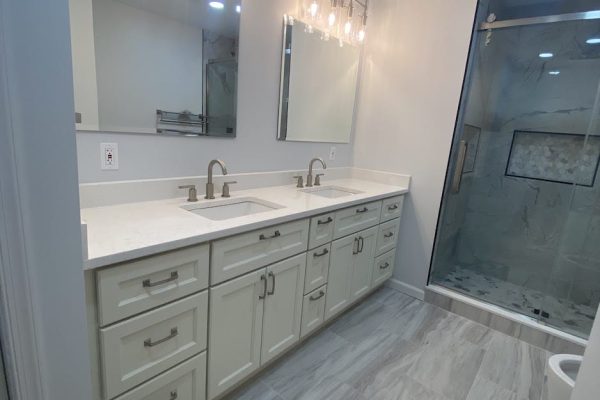 Modern bathroom remodel with double vanity, quartz countertops, lighted mirrors, and walk-in glass shower in PA