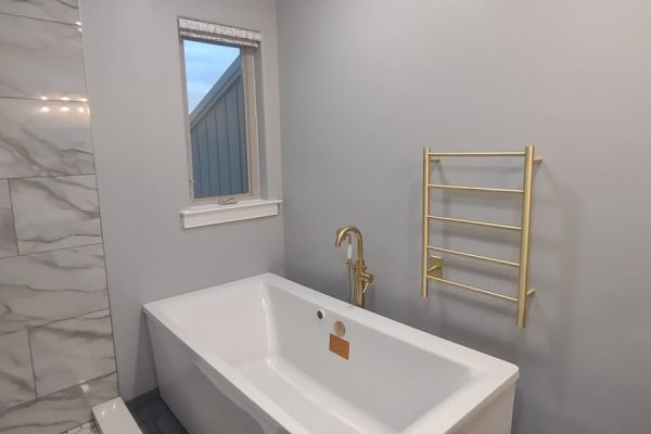 Contemporary bathroom remodel with freestanding bathtub, gold fixtures, and marble tile shower in PA