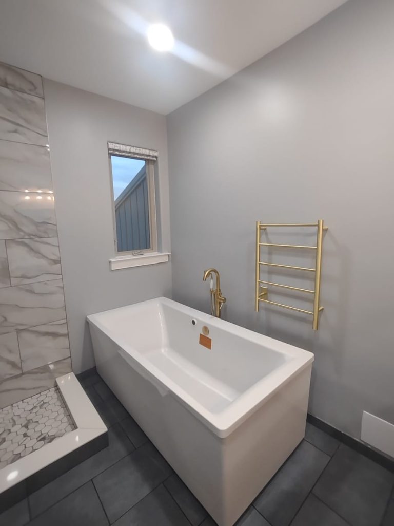 Contemporary bathroom remodel with freestanding bathtub, gold fixtures, and marble tile shower in PA