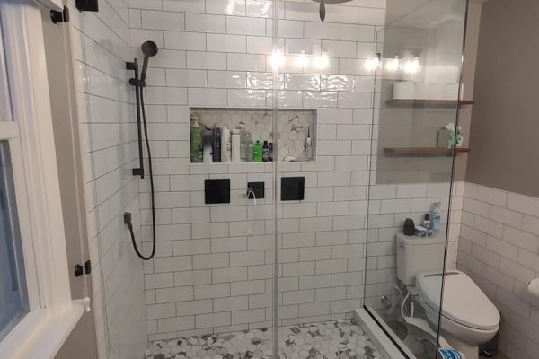 Modern bathroom with a frameless glass shower, dual rainfall showerheads, subway tile walls, and a built-in niche in PA