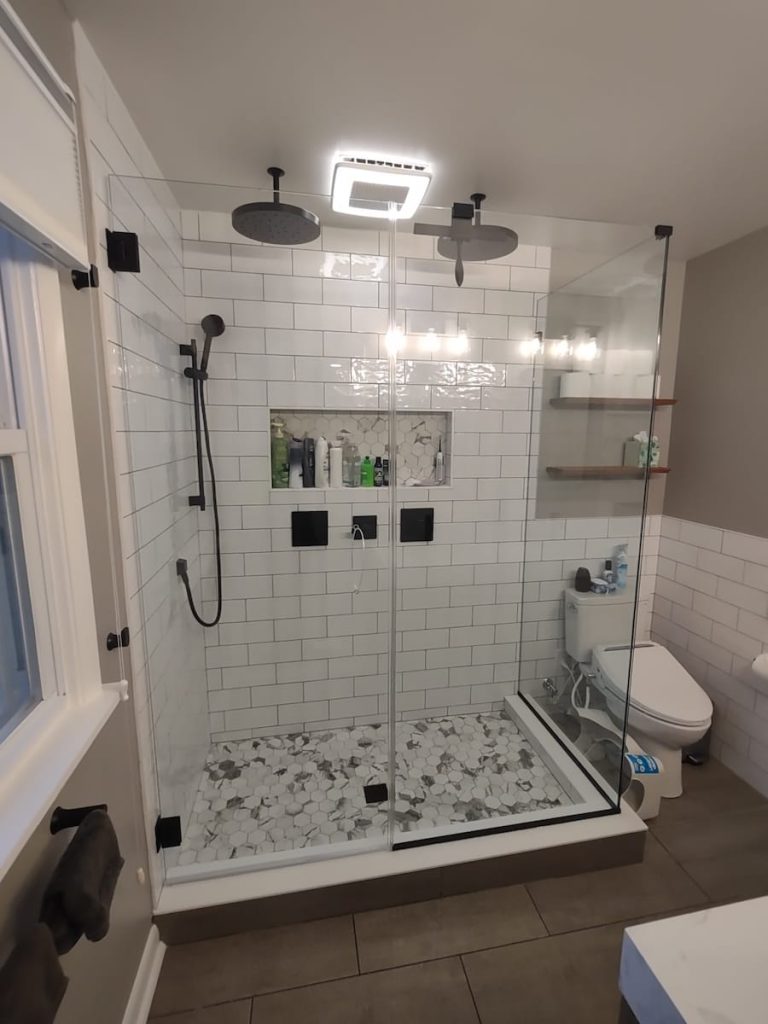 Modern bathroom with a frameless glass shower, dual rainfall showerheads, subway tile walls, and a built-in niche in PA