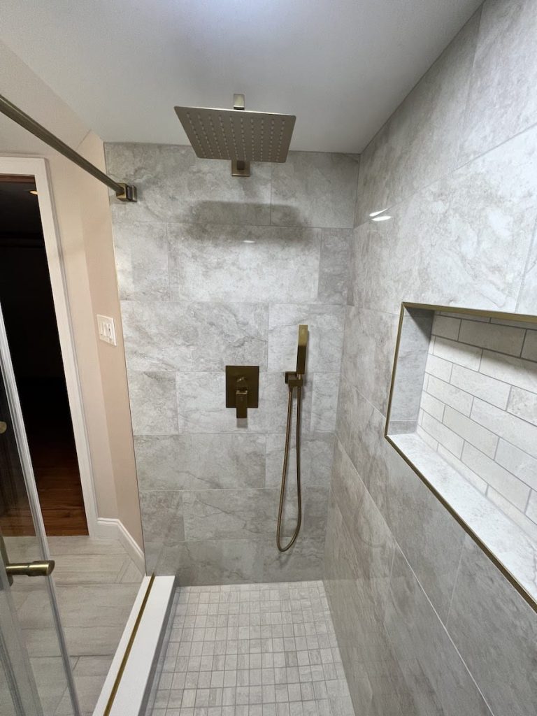 Luxury shower remodel featuring a rainfall showerhead, large gray tiles, and built-in niche in PA